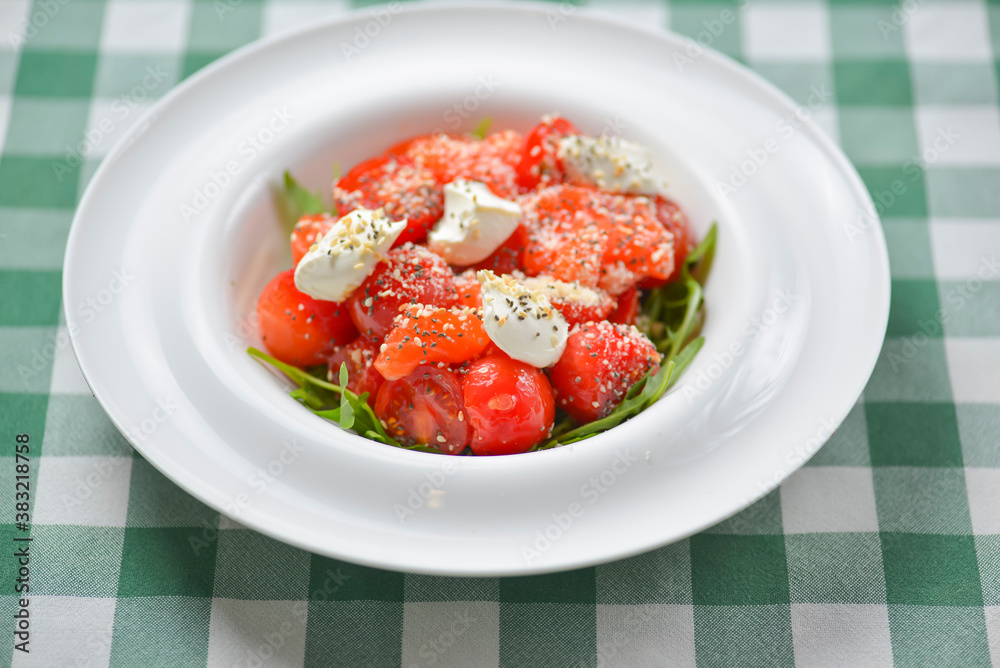 Tomato and salmon salad with cheese and spices. Traditional Italian cuisine, Italian concept. Tomato and salmon salad with cheese and spices. Traditional Italian cuisine, Italian concept.
