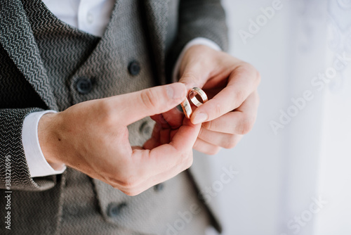 A groom holding wedding rings in his hands closeup