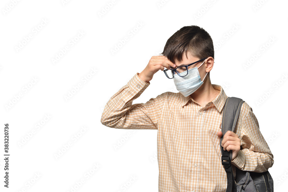Caucasian white schoolboy wearing a protective mask touching a sick head on a white isolated background Caucasian white schoolboy wearing a protective mask touching a sick head on a white isolated background