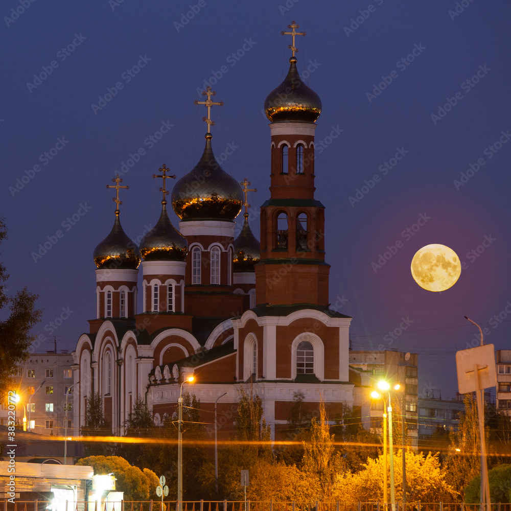 Nativity of Christ Cathedral at Stepants 5 in Omsk and the rising full moon next to the church. Full moon over the temple. Nativity of Christ Cathedral at Stepants 5 in Omsk and the rising full moon next to the church. Full moon over the temple.