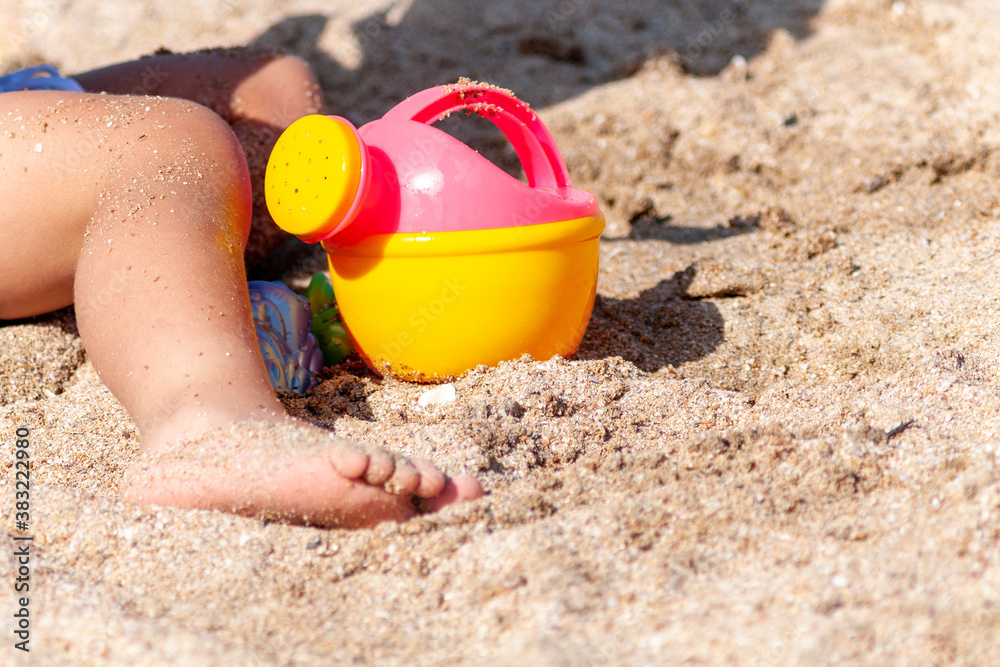 child playing with toy watering can on the beach on asummer day child playing with toy watering can on the beach on asummer day