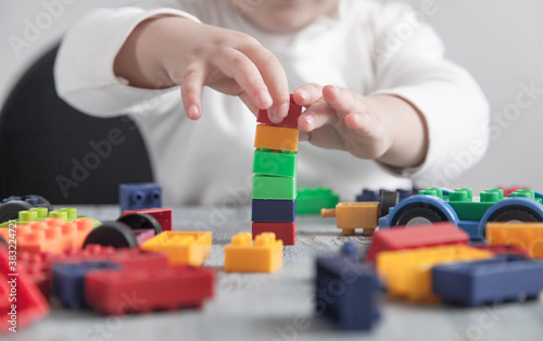 Little girl playing with colorful construction plastic cubes.