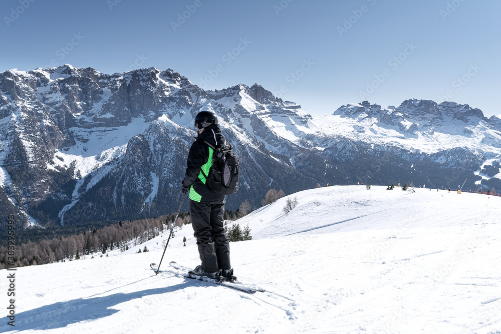 A man stands on the side of a mountain against the backdrop of the snow-capped Dolomites. Concept for sports, landscape, people.