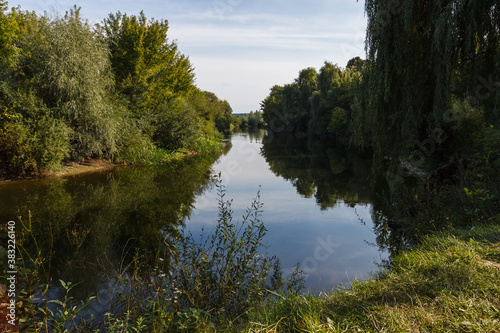 Fototapeta Naklejka Na Ścianę i Meble -  View of a picturesque landscape with a river. Landscape overlooking the riverbed. Overgrown shores