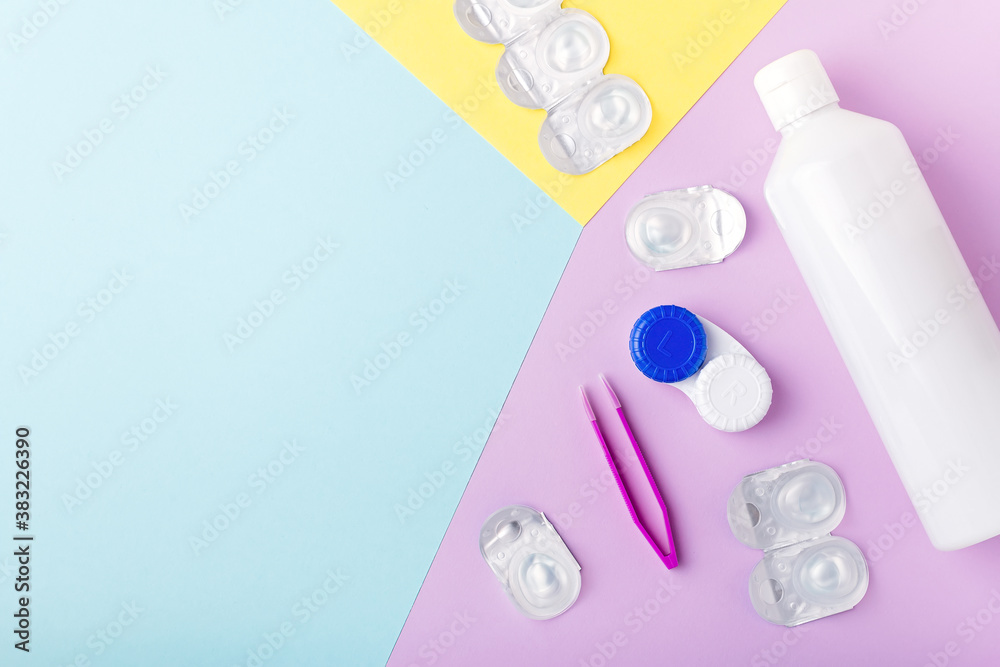 Contact lens kit with bottle of lens solution, case, tweezer on multicolor background, copy space, top view Contact lens kit with bottle of lens solution, case, tweezer on multicolor background, copy space, top view