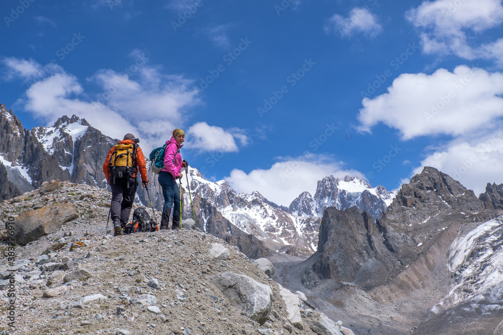 Fototapeta premium Not young spouses and their dog climbed to a height of 3300 meters above sea level. They are very happy that they were able to go so far. They jump, laugh against the background of snowy mountains.