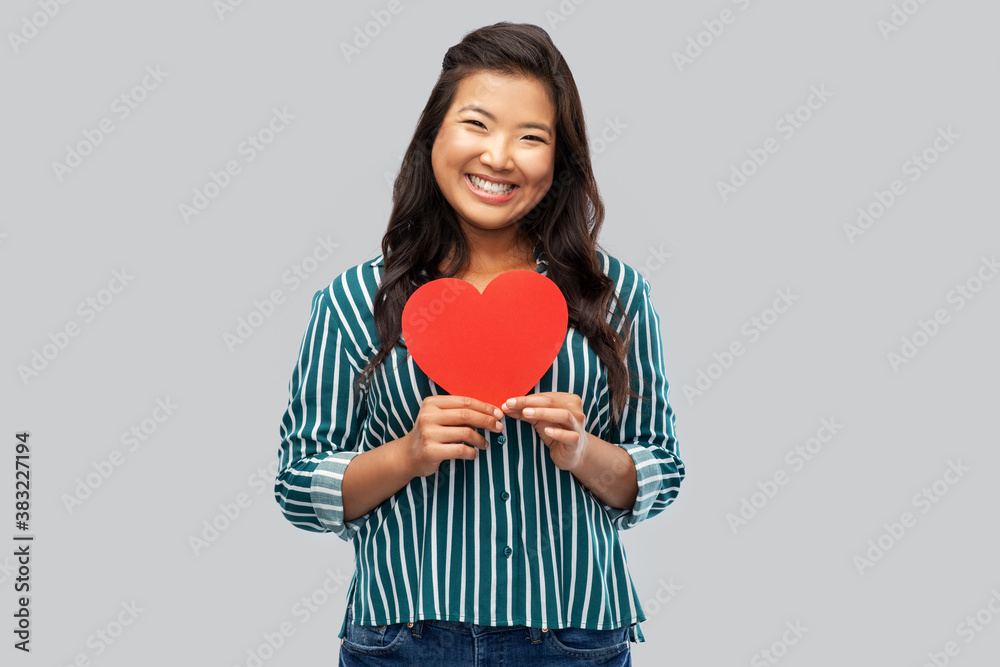 love, charity and valentines day concept - happy asian young woman with red heart over grey background love, charity and valentines day concept - happy asian young woman with red heart over grey background