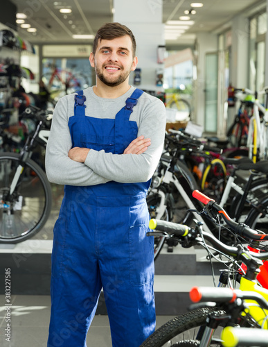 ...Portrait of young professional man worker standing in bicycle store