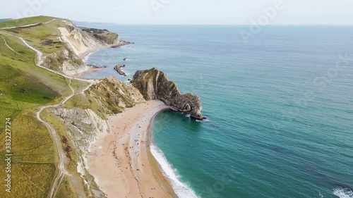 Aerial drone shot tracking around to reveal the famous Durdle Door rock formation on the jurassic coast in Dorset.