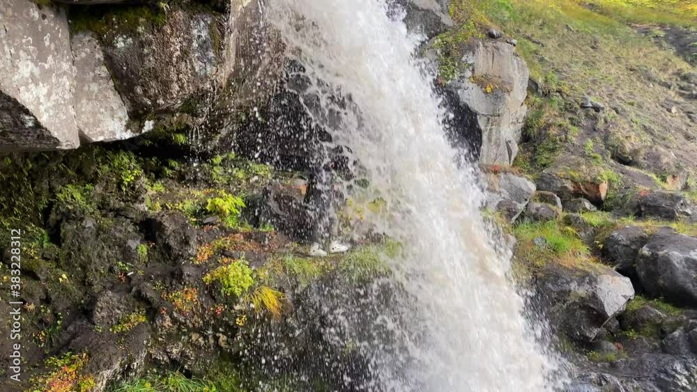 Photographer stands under a beautiful picturesque waterfall and takes pictures of nature. Amazing autumn landscape. Travel to the Kamchatka Peninsula. Photographer stands under a beautiful picturesque waterfall and takes pictures of nature. Amazing autumn landscape. Travel to the Kamchatka Peninsula.