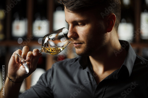 Bokal of white wine on background, male sommelier appreciating drink photo