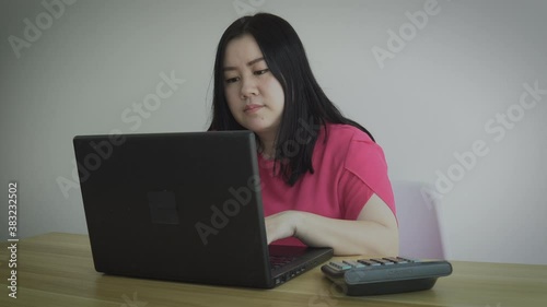 young Asian woman or small business owner or entrepreneur using calculator