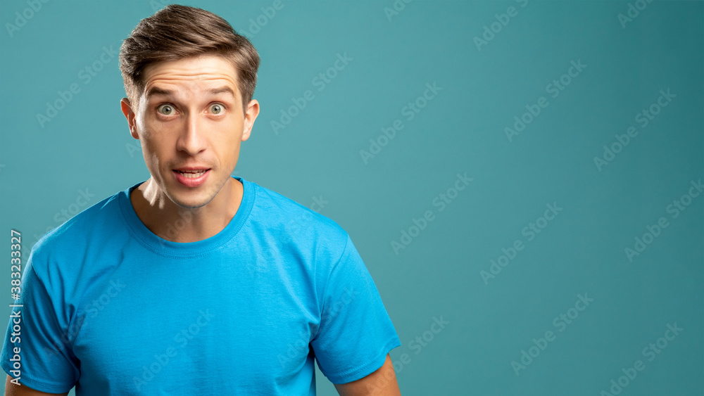 Fototapeta premium Angry male portrait. Critical abusing. Aggressive emotion. Young expressive man looking at camera offending isolated on blue copy space.