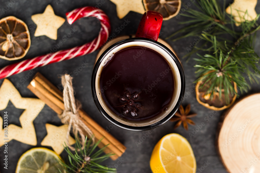 hot tea in a red mug in a new year's atmosphere. Christmas morning. A mug with a drink next to Christmas tree branches, oranges, spices and cookies