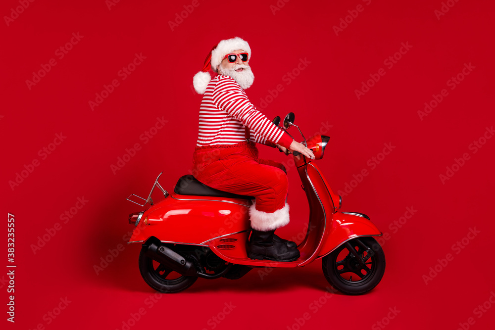 Full length body size profile side view of his he handsome cheery overweight bearded Santa father riding moped road way rental service traveler isolated bright vivid shine vibrant red color background Full length body size profile side view of his he handsome cheery overweight bearded Santa father riding moped road way rental service traveler isolated bright vivid shine vibrant red color background