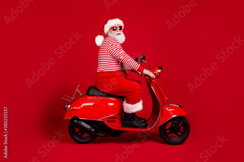 Full length body size profile side view of his he handsome cheery overweight bearded Santa father riding moped road way rental service traveler isolated bright vivid shine vibrant red color background