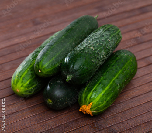 Many ripe juicy cucumbers on wooden surface closeup