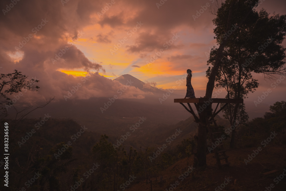 Fototapeta premium Silhouette of a girl in a long dress stands with Bali landmark volcano Agung view. Travel blogger, Indonesia best sunset point destination. Woman retreat. High quality photo