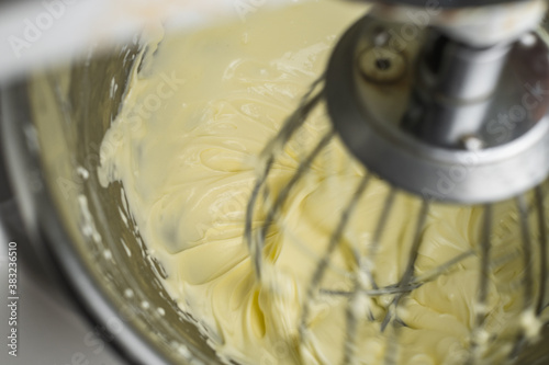 Close up creaming cream cheese to soften in the food mixer machine bowl for making cheesecake or other bakery products.