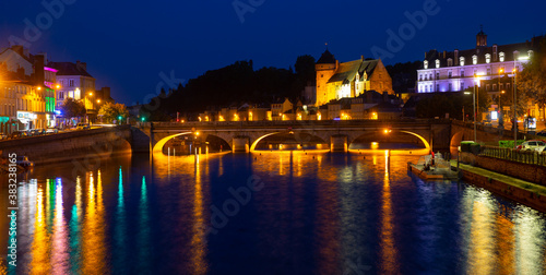 Scenic view of lighted ancient Laval castle on banks of Mayenne river at summer dusk  France