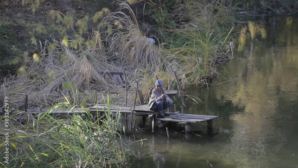 Kid fishing in a river, sitting on a wood pontoon Kid fishing in a river, sitting on a wood pontoon