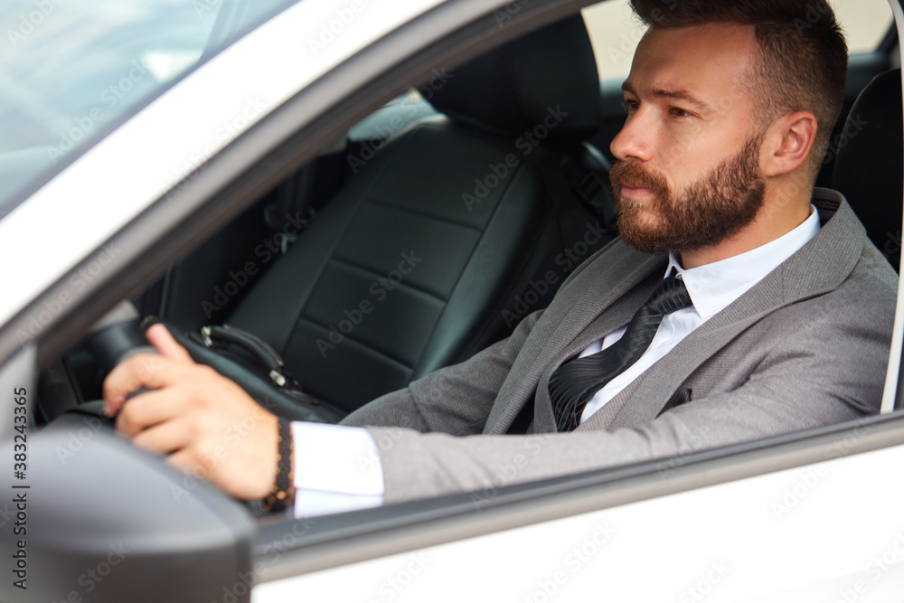 successful caucasian man in formal suit driving a car, sit inside of automobile. alone