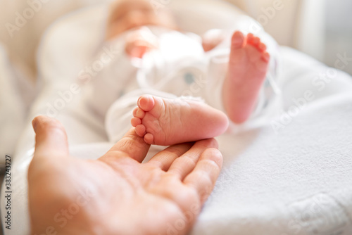 Father holding in the hands feet of newborn baby. Baby little feet in parents hand. Feet skin care closeup. Happy family conception.