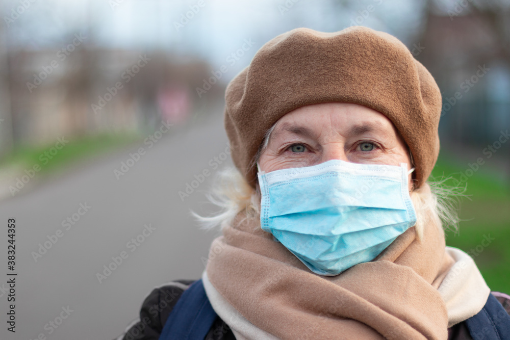 Coronavirus, adult 40 50 years woman in a medical mask and warm clothes looking at the camera, outdoors. Protection against contagious disease, covid 19