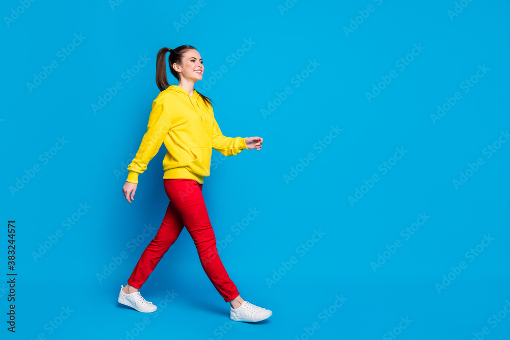 Full length body size profile side view of her she nice attractive lovely proud glad cheerful cheery girl walking strolling isolated over bright vivid shine vibrant blue color background