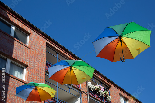 Drei aufgespannte, bunte Regenschirme hängen in einer Strassse © sweasy