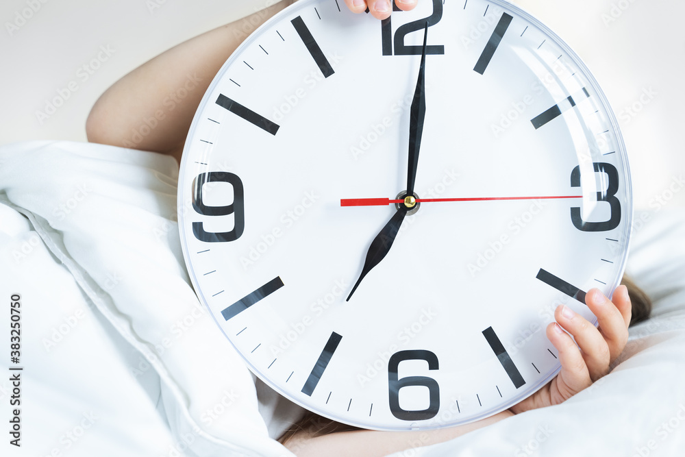 Little sleeping girl with big, huge clock in hands. Early morning wake up before kindergaten,school. White pillow, blanket in bed. Sleepy child. Sweet dreams. Bedtime. Correct mode of children's rest Little sleeping girl with big, huge clock in hands. Early morning wake up before kindergaten,school. White pillow, blanket in bed. Sleepy child. Sweet dreams. Bedtime. Correct mode of children's rest