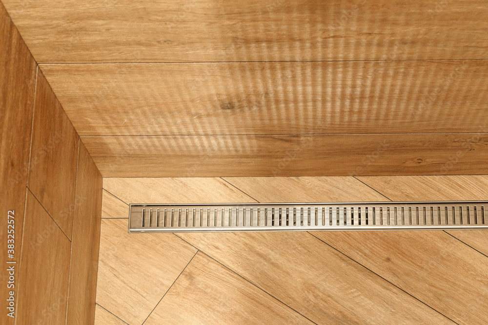 drain in the form of a mesh in the bathroom with wood-effect tiles drain in the form of a mesh in the bathroom with wood-effect tiles