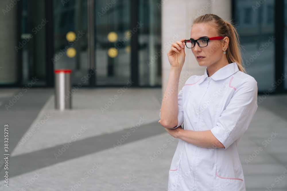 A young beautiful female doctor holds a stethoscope . The concept of a European doctor, copy space.