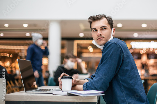 thoughtful young man sitting at a table in a cafe