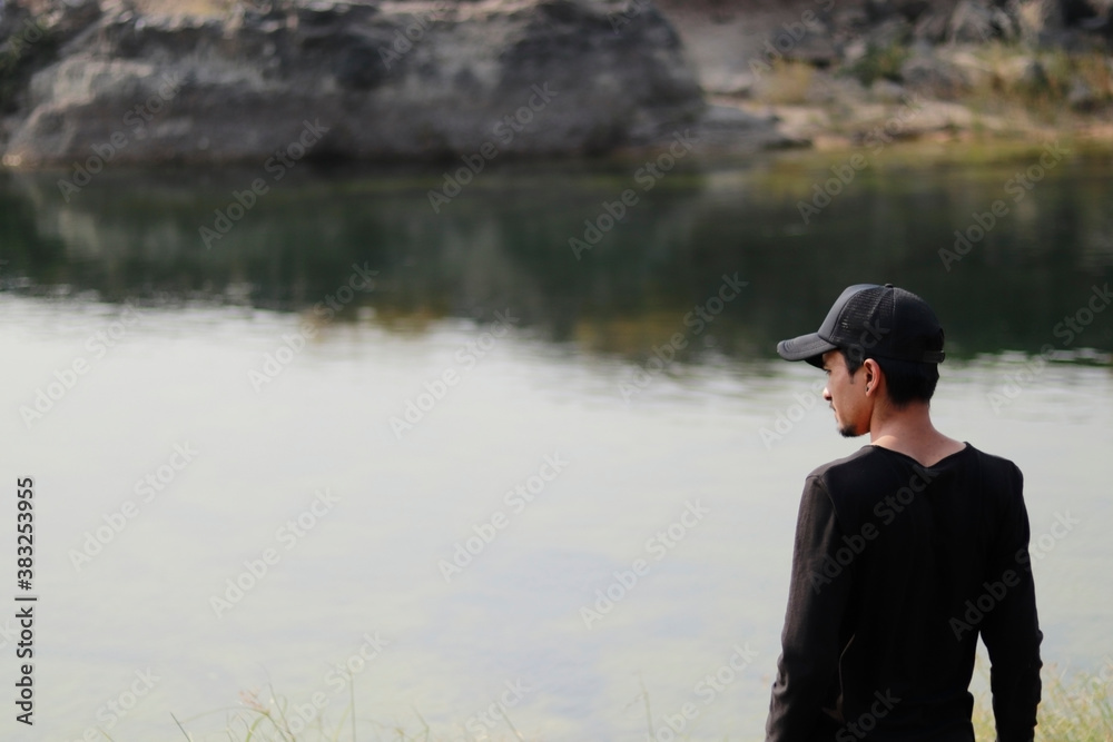 Fototapeta premium young indian man standing against still water of river