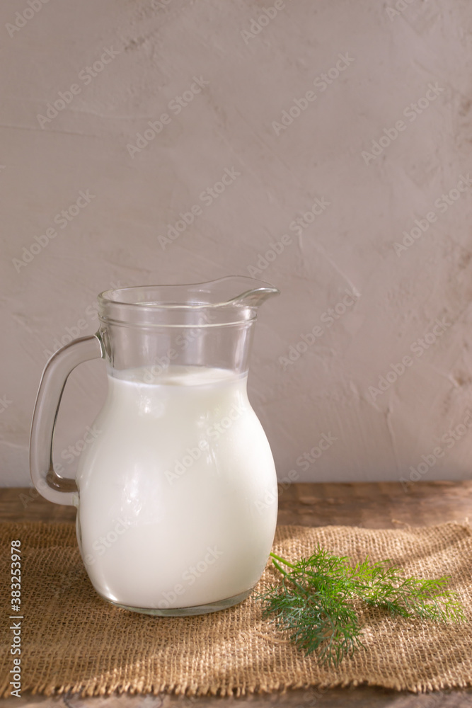 Glass jug with Ayran drink and a sprig of dill on a wooden background. Fermented product concept. Vertical orientation. Copy space. Glass jug with Ayran drink and a sprig of dill on a wooden background. Fermented product concept. Vertical orientation. Copy space.