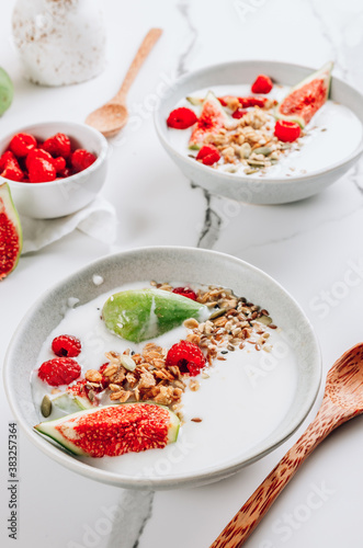 Granola with yogurt, figs and raspberries in bowls