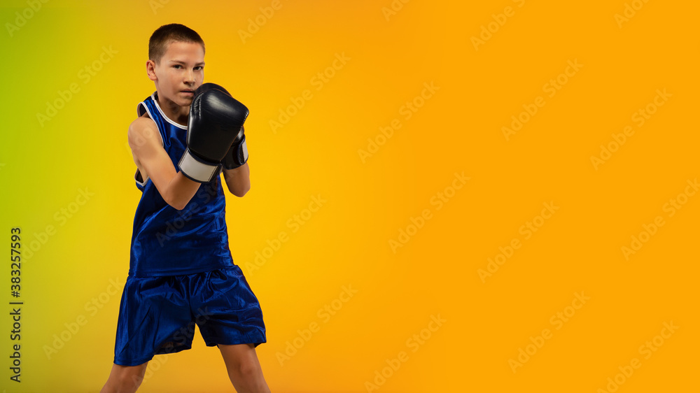 Competitive. Teenage professional boxer training in action, motion isolated on gradient background in neon light. Kicking, boxing. Concept of sport, movement, energy and dynamic, healthy lifestyle.