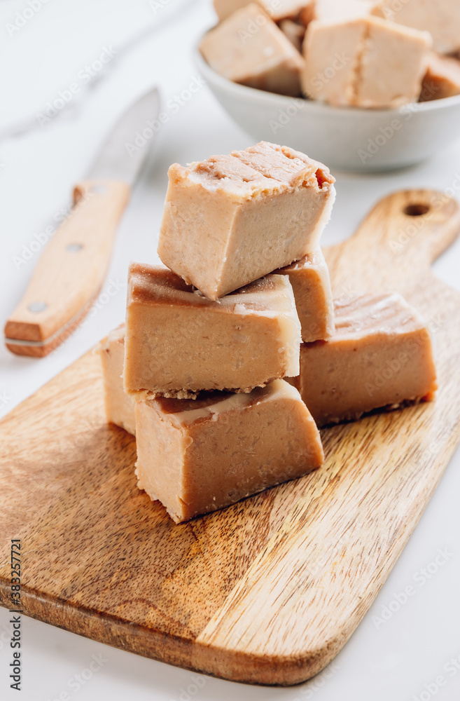 Raw vegan peanut butter fudge on a white marble background.