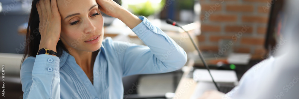 Woman holding her head in stress employer shows clock. Working time planning and deadlines concept