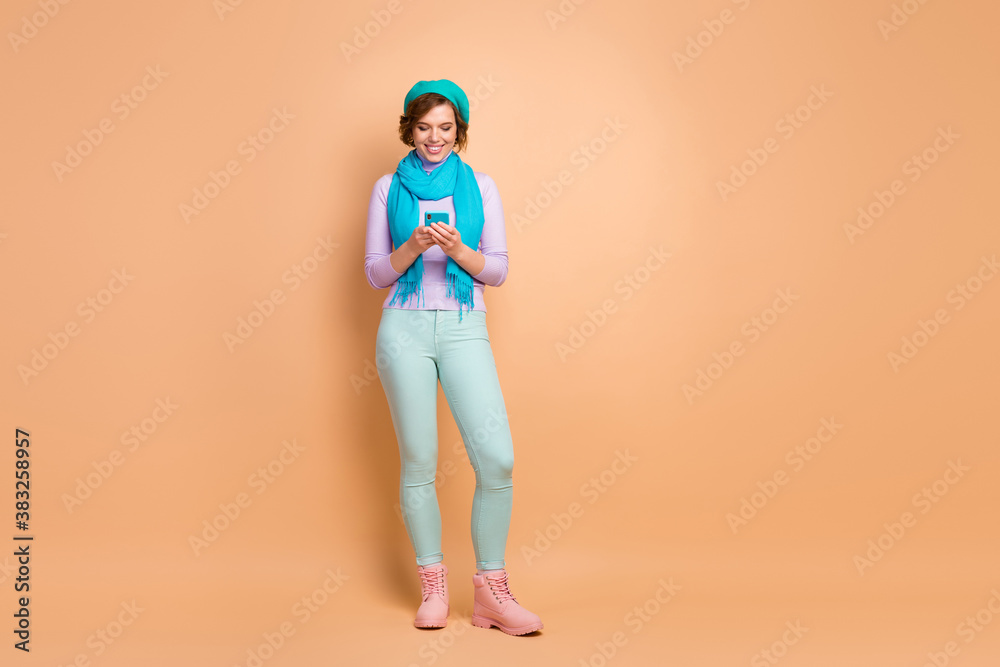 Full length body size view of her she nice attractive lovely pretty cheerful cheery girl using digital device spending free spare time isolated over beige pastel color background Full length body size view of her she nice attractive lovely pretty cheerful cheery girl using digital device spending free spare time isolated over beige pastel color background