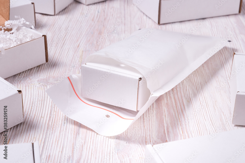 Lot of white bubble envelopes and carton box on wooden table