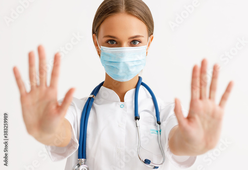 concept of fighting coronavirus infection. a doctor in a protective medical mask shows stop symbol with hands