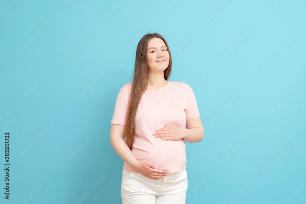 happy young pregnant woman in pink t-shirt on blue background happy young pregnant woman in pink t-shirt on blue background