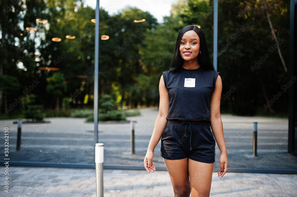 Fashionable feminist african american woman wear in black t-shirt and shorts, posed outdoor. Fashionable feminist african american woman wear in black t-shirt and shorts, posed outdoor.