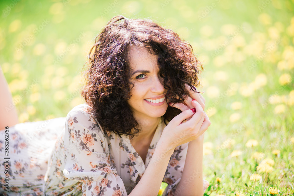 Young attractive woman with curly long hair posing in spring blooming garden, apple trees Young attractive woman with curly long hair posing in spring blooming garden, apple trees