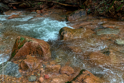 Small torrent in the forest with red porphyry stones.