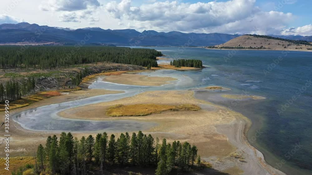 Aerial view flying over the marsh at Hebgen Lake along the shoreline as the wind blows ripples in the water.
