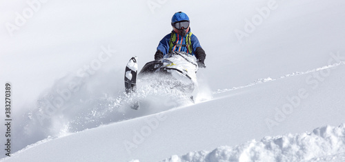 snowmobilers make a turn in a snow-white valley. COPY SPACE. Extreme Snowmobile Ride & Racing. a bright suit and a snow motorcycle. snowmobilers sports riding. high resolution photo
