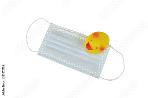 Yellow rubber duck toy with protective medical mask isolated on a white background, coronavirus and respiratory disease preventive concept